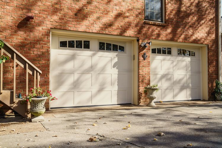 Two white garage doors recessed on a brick wall